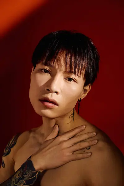 A stylish Asian man highlights his tattoos and confidence in a vibrant setting. — Stock Photo