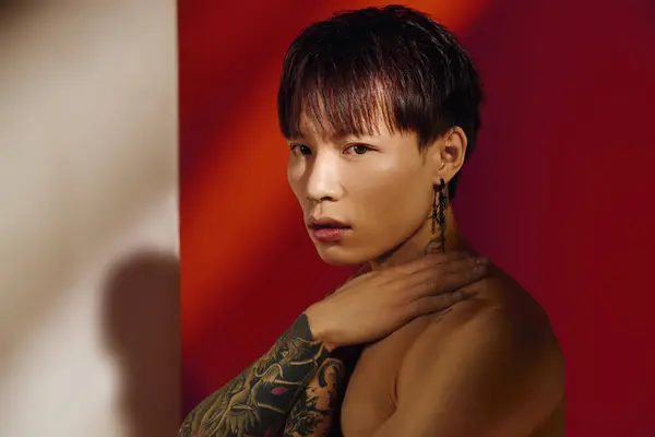 Hombre tatuado guapo posa con confianza, mostrando su estilo contra colores vibrantes. - foto de stock