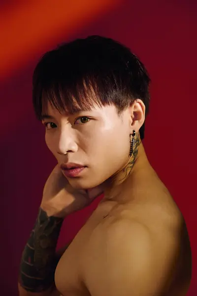A stylish young man poses confidently against a bold red background. — Stock Photo