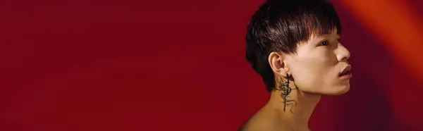 A handsome asian man showcases his unique style and striking features in a bold red setting. — Stock Photo