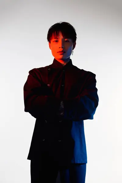 A stylish young man stands confidently in a sleek black outfit under bright lighting. — Stock Photo