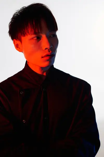 A young Asian man poses confidently against a creatively lit, colorful backdrop. — Stock Photo
