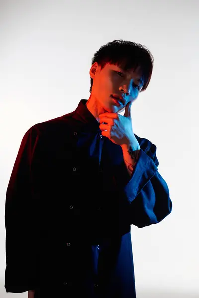 A stylish young Asian man stands confidently, deep in thought and showcasing his fashion. — Stock Photo