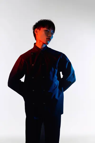 A handsome young man stands confidently, showcasing his stylish outfit with artistic lighting. — Stock Photo
