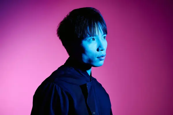 A handsome young Asian man poses stylishly against a vibrant, colorful backdrop. — Stock Photo