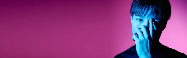 A handsome young man displays his stylish look with confidence in front of a colorful backdrop. — Stock Photo