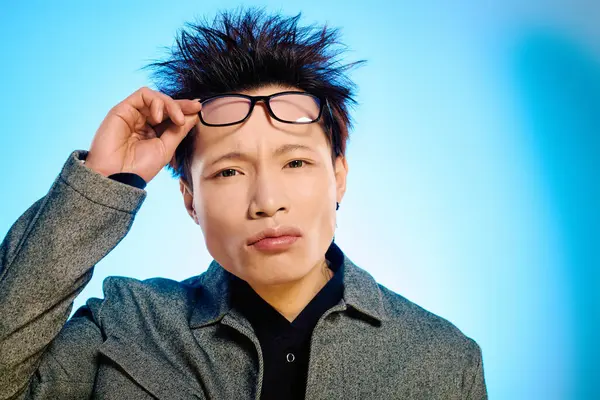 A young man stylishly adjusts his glasses, exuding confidence amid bright colors. — Stock Photo