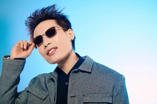 A handsome Asian man showcases his fashion sense while adjusting his sunglasses with flair. — Stock Photo