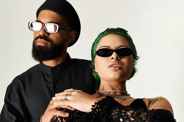 Elegante pareja joven con diversos fondos posa con confianza con gafas de sol en la iluminación del estudio. - foto de stock