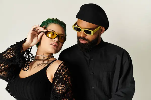 A stylish young couple, one with green hair, poses confidently in sunglasses in a studio. — Stock Photo