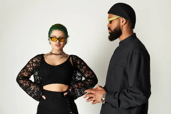 Young couple showcases their unique fashion sense while striking poses in the studio. — Stock Photo