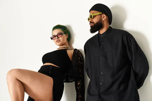Um jovem casal na moda com origens diversas posa com confiança em um estúdio brilhante. — Fotografia de Stock