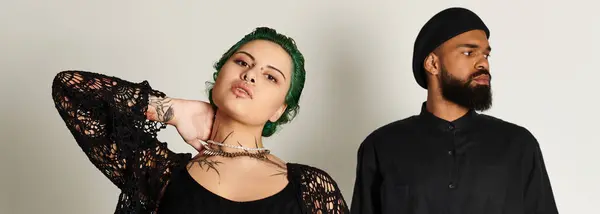A stylish young couple poses confidently in a studio with their outfits. — Stock Photo