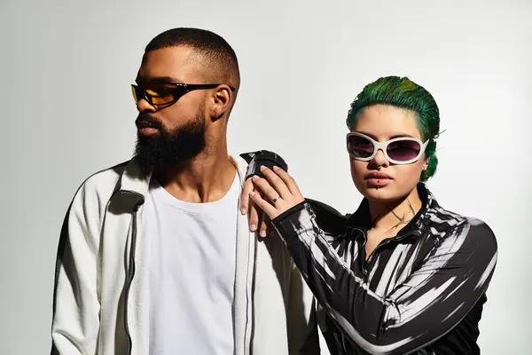 A fashionable multicultural couple poses confidently in a vibrant studio, showcasing unique styles. — Stock Photo