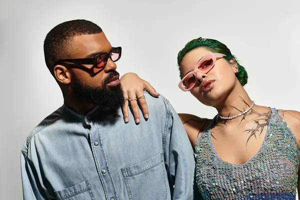 A young couple showcases their stylish outfits and diverse backgrounds while posing confidently. — Stock Photo