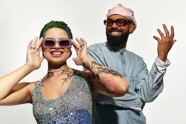 A stylish multicultural couple poses confidently in trendy outfits, radiating joy in the studio. — Stock Photo