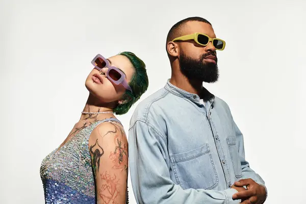 Young couple exudes confidence while posing together in fashionable outfits and bold sunglasses. — Stock Photo