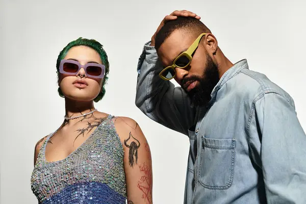 A fashionable multicultural couple poses confidently while wearing stylish sunglasses in a studio. — Stock Photo