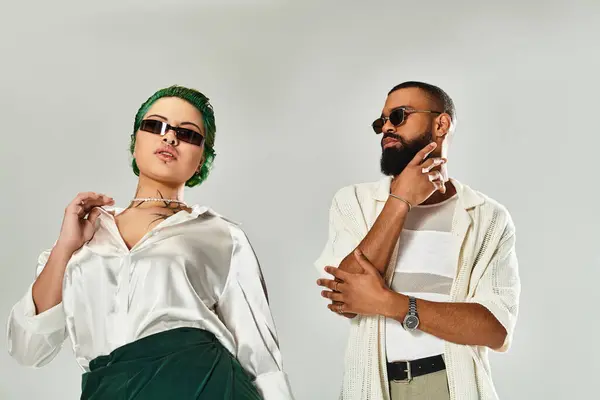 Multicultural couple showcases their trendy outfits in a bright studio while posing together. — Stock Photo