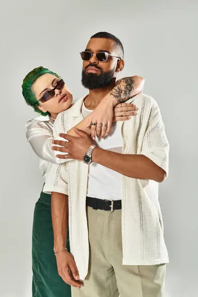 Una pareja multicultural muestra juguetonamente su moda única bajo luces de estudio. - foto de stock