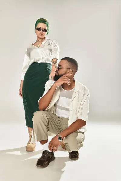 Multicultural couple showcases trendy outfits and stylish sunglasses in a studio environment. — Stock Photo
