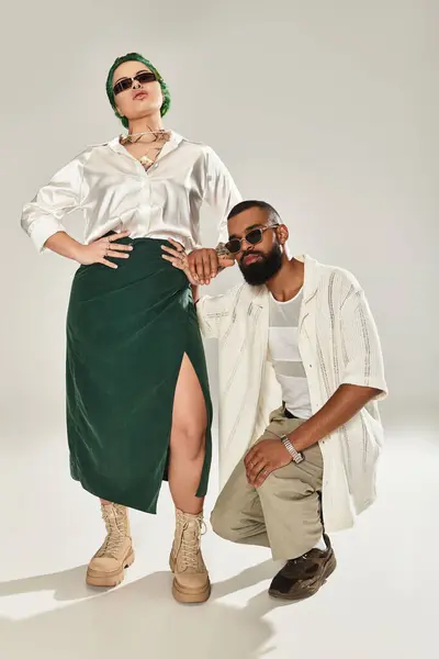 Una pareja joven de moda posa con confianza en un estudio elegante, mostrando sus trajes únicos. - foto de stock