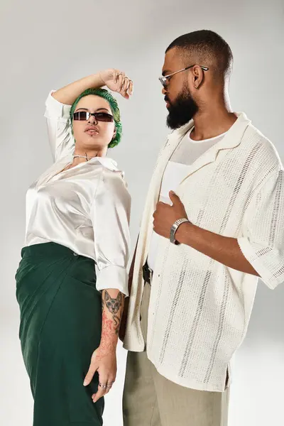 Um casal elegante mostra seu senso de moda diversificada enquanto posando em um ambiente de estúdio chique. — Fotografia de Stock