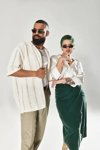 Una elegante pareja multicultural posa con confianza en gafas de sol, irradiando encanto. - foto de stock