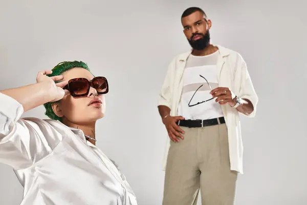 A stylish couple wears vibrant outfits and sunnies, posing together with flair. — Stock Photo