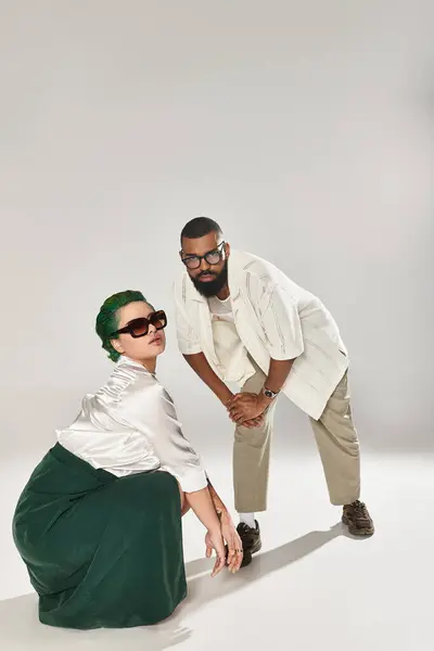 Um casal na moda posa com confiança, mostrando seus estilos únicos e óculos de sol em um estúdio. — Fotografia de Stock