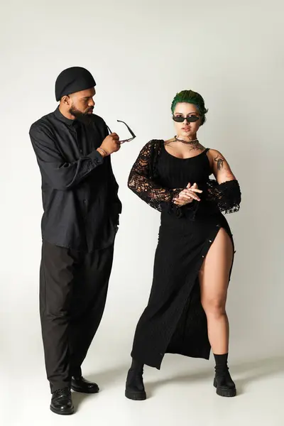 Young couple showcases their unique fashion sense while posing confidently in a studio setting. — Stock Photo