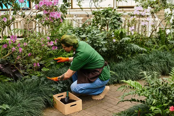 A young woman tends to colorful plants in a bright, lush greenhouse. — Stock Photo