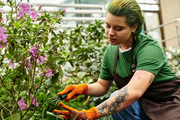 A young woman in a greenhouse joyfully nurtures blooming flowers. — Stock Photo