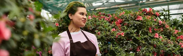 A young woman tends to vibrant flowers in a lush greenhouse. — Stock Photo