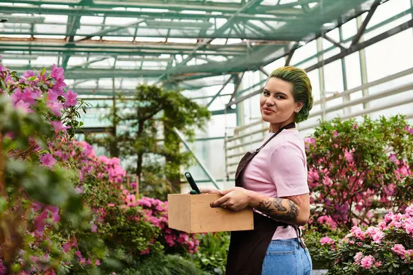 A young woman joyfully tends to vibrant flowers in a greenhouse. — Stock Photo