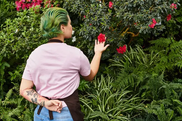 A young woman in a cozy greenhouse lovingly cares for colorful flowers while enjoying nature. — Stock Photo