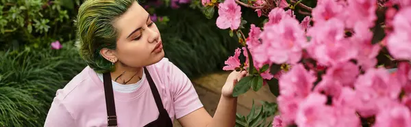 Focused young woman engages with blooming flowers while cultivating her passion in a greenhouse. — Stock Photo