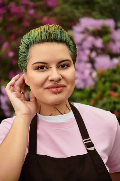 A young woman with green hair smiles while caring for plants in a colorful greenhouse. — Stock Photo