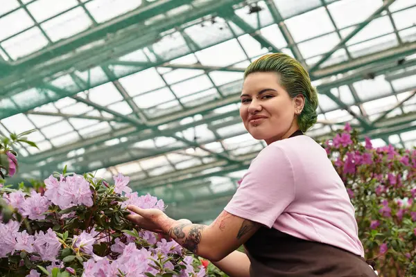 Amidst beautiful blooms, a young woman passionately cares for plants in a greenhouse setting. — Stock Photo