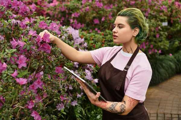 Energetic young woman engages with colorful flowers while working in a lively greenhouse setting. — Stock Photo