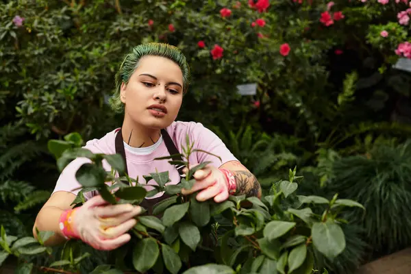 In a vibrant greenhouse, a woman prunes and cares for lush plants and blooming flowers. — Stock Photo