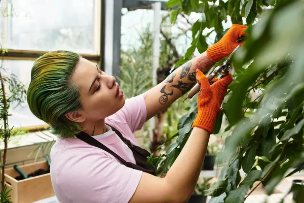 Focused young woman diligently pruning plants in a bright and lively greenhouse setting — Stock Photo