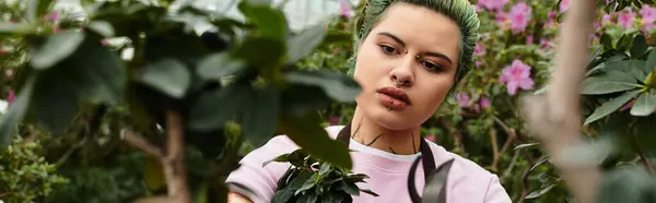 En un exuberante invernadero, una mujer poda cuidadosamente plantas vibrantes y flores coloridas. - foto de stock