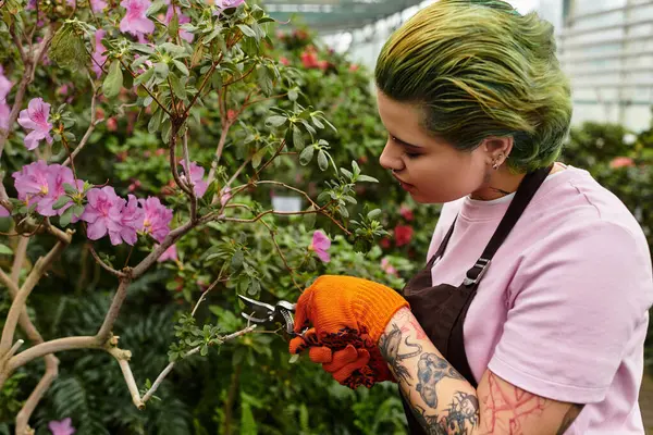 A lively young woman prunes beautiful flowers in a greenhouse, embracing her passion. — Stock Photo