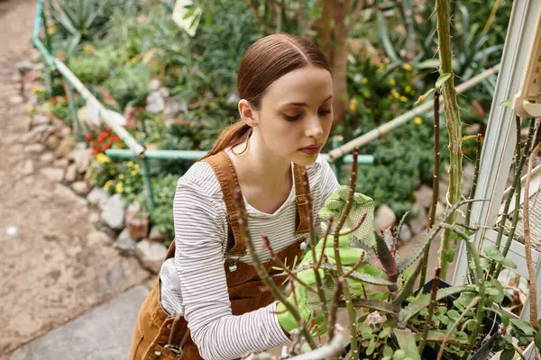 A young woman tends to vibrant plants in a colorful greenhouse. — Stock Photo