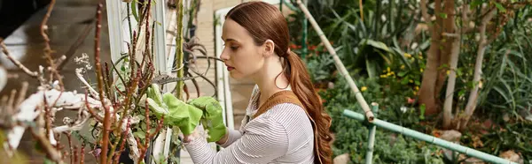 Young woman focuses on tending to plants in a vibrant greenhouse filled with greenery. — Stock Photo