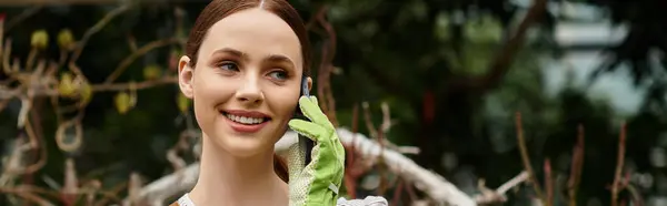 Young woman delights in her garden, phone in hand, surrounded by flourishing green plants. — Stock Photo
