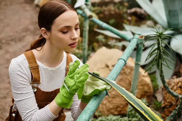 In a peaceful greenhouse, a young woman tenderly cares for a potted plant. — Stock Photo