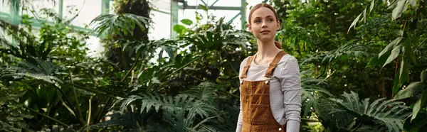 Young woman admires the stunning array of plants while standing in a bright greenhouse environment. — Stock Photo