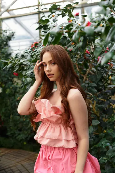 In a calm greenhouse, a young woman gracefully enjoys the vibrant greenery around her. — Stock Photo